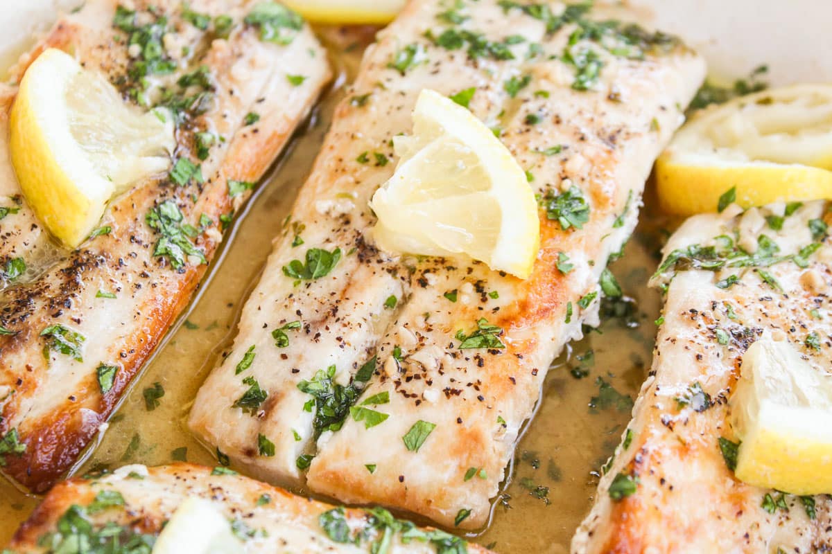 up close shot of mahi mahi topped with lemon in a skillet