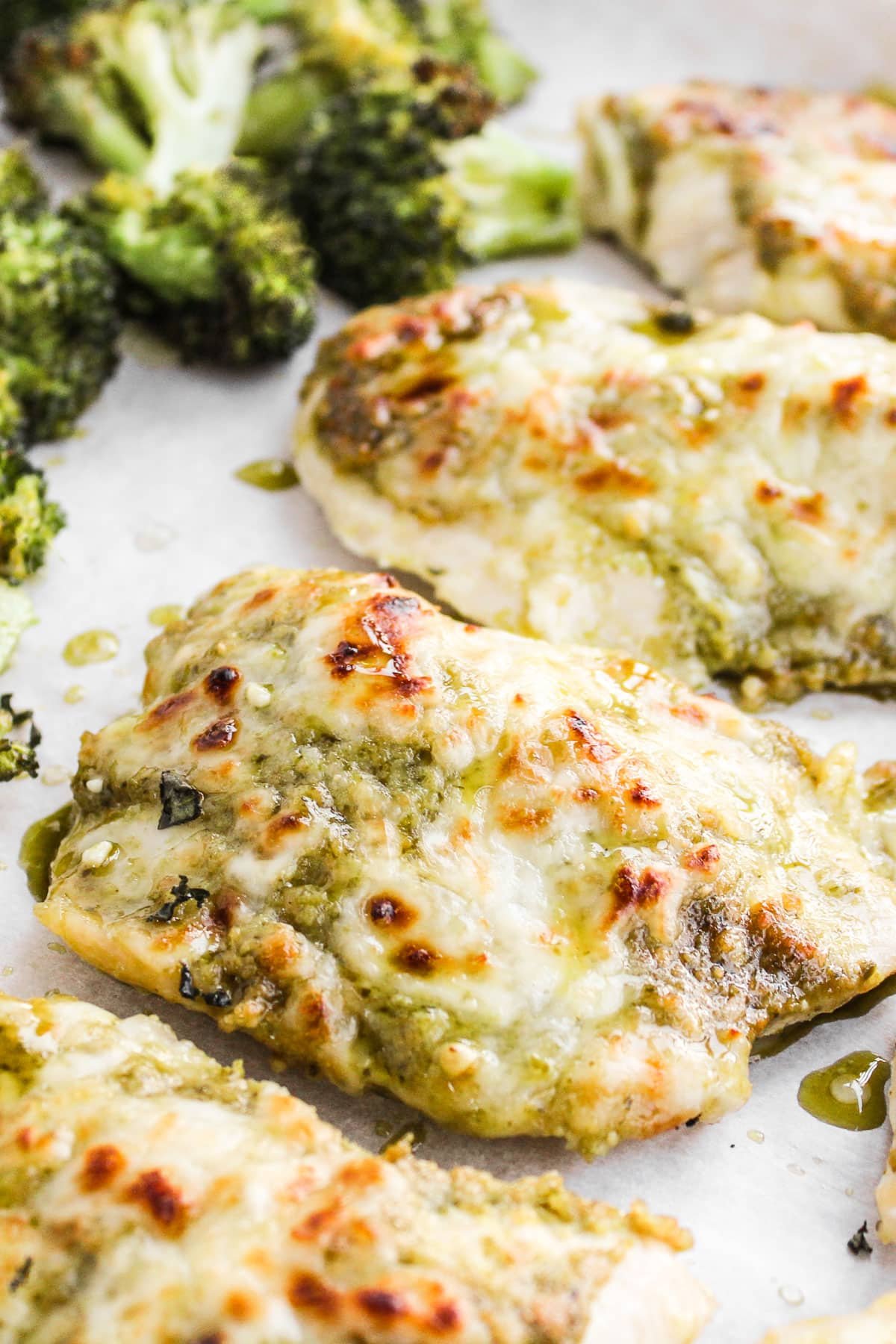 Pesto chicken baked on a sheet pan with broccoli